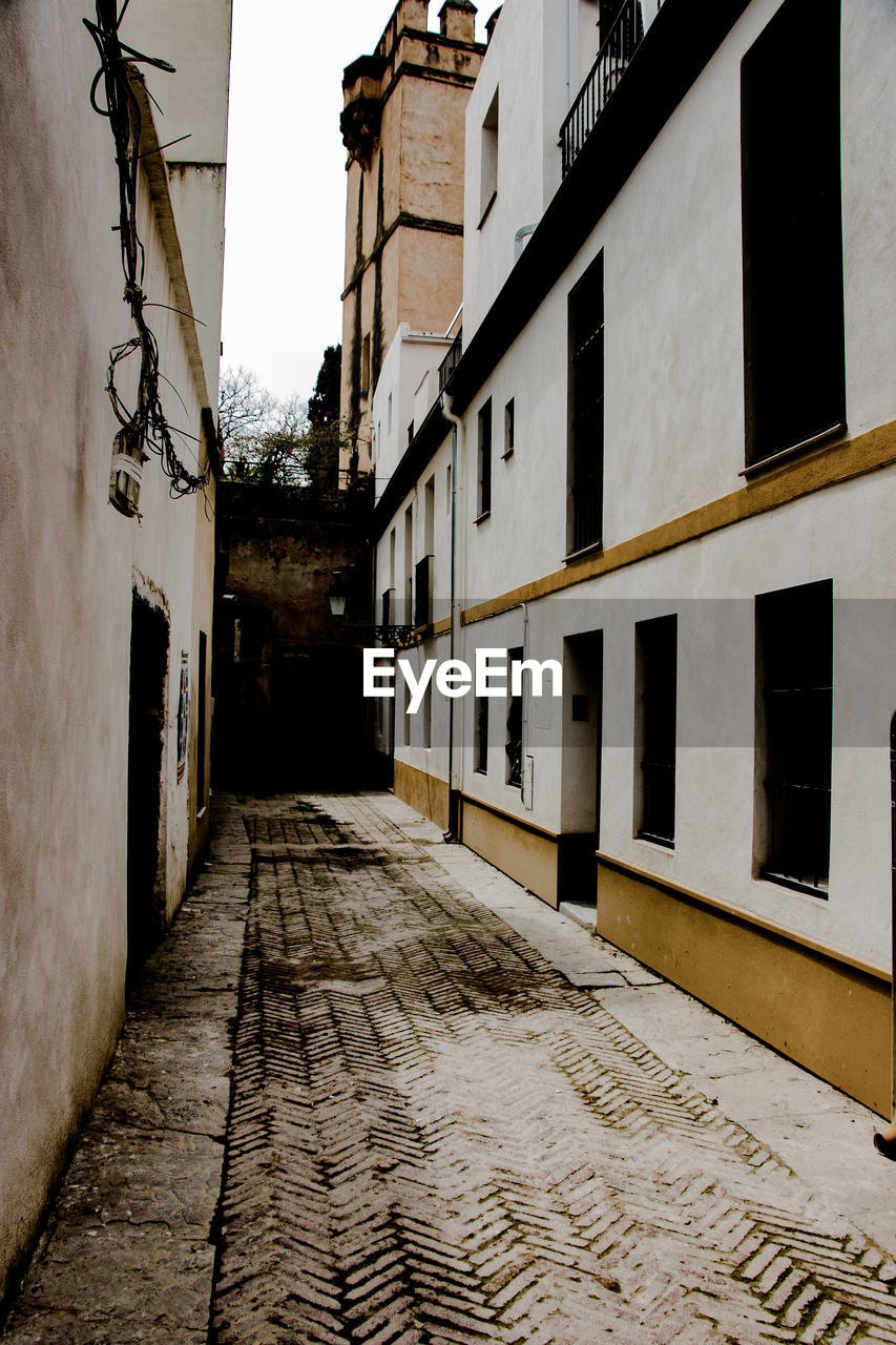 EMPTY FOOTPATH AMIDST BUILDINGS