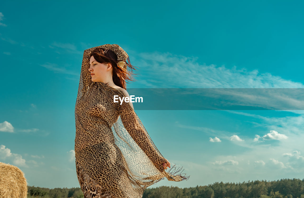 Rear view of woman standing on field against sky