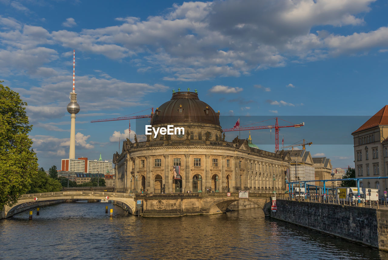 BRIDGE OVER RIVER BY BUILDINGS AGAINST SKY