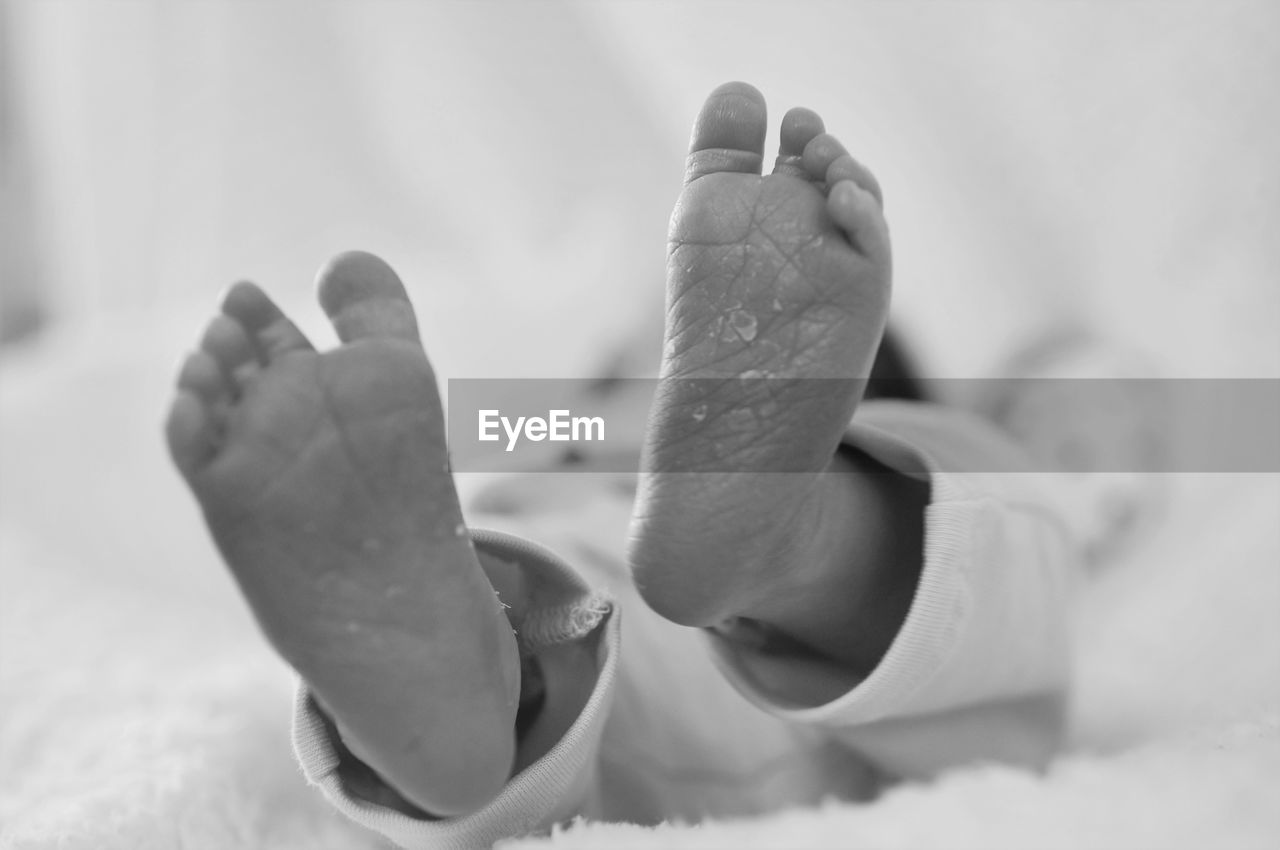 Low section of baby relaxing on bed