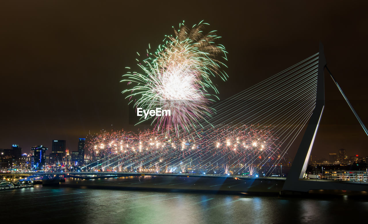 Firework exploding over erasmus bridge at night