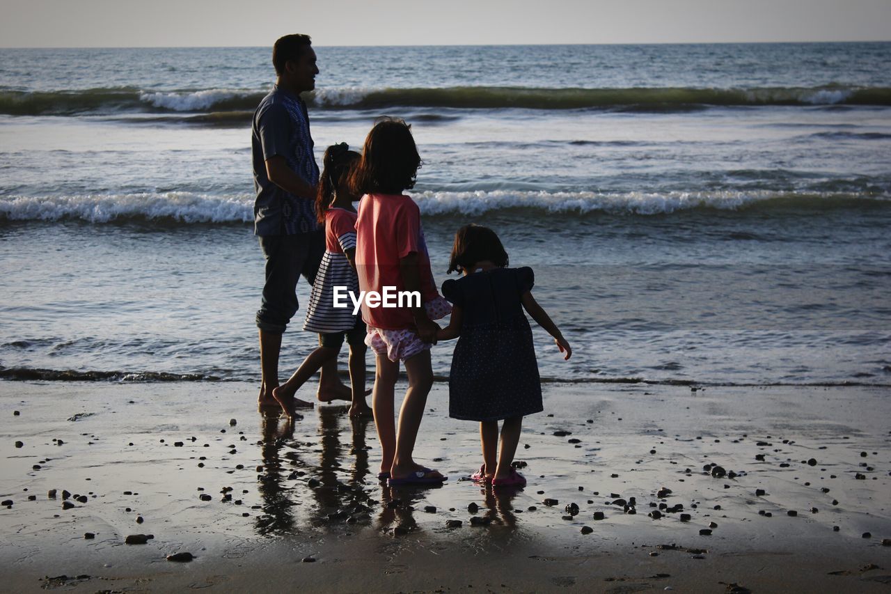 REAR VIEW OF FRIENDS WALKING ON BEACH