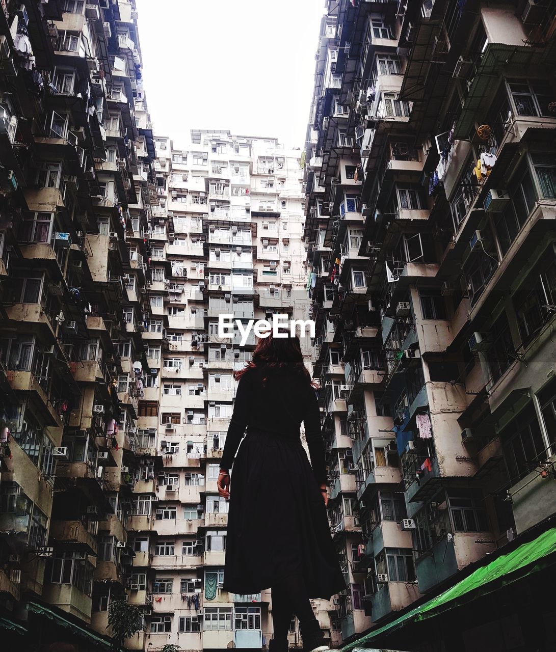 Rear view of woman standing amidst buildings in city