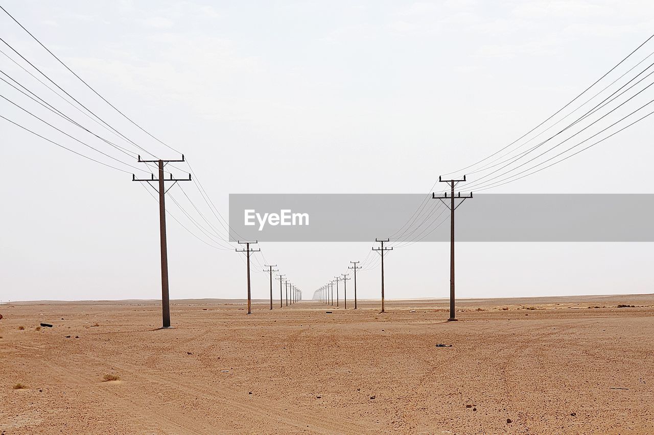 ELECTRICITY PYLON BY LAND AGAINST SKY