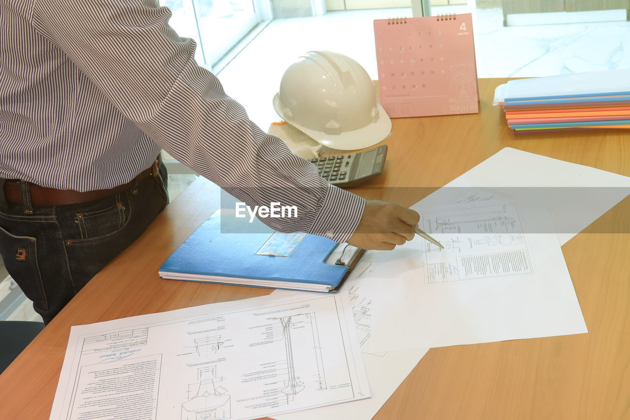 HIGH ANGLE VIEW OF MAN WORKING ON TABLE WITH PAPER