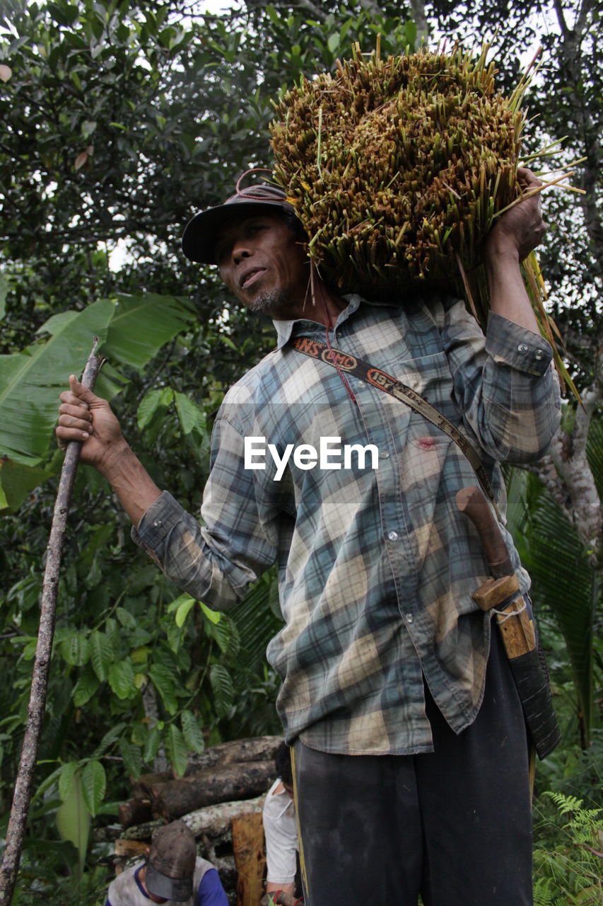 Low angle view of farmer carrying crop on shoulder