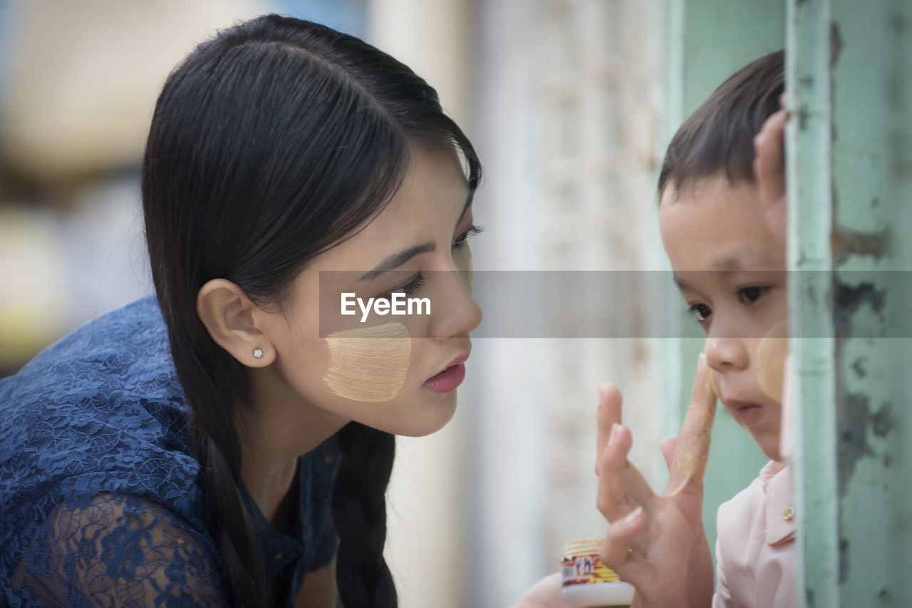 Woman applying cream on face of boy