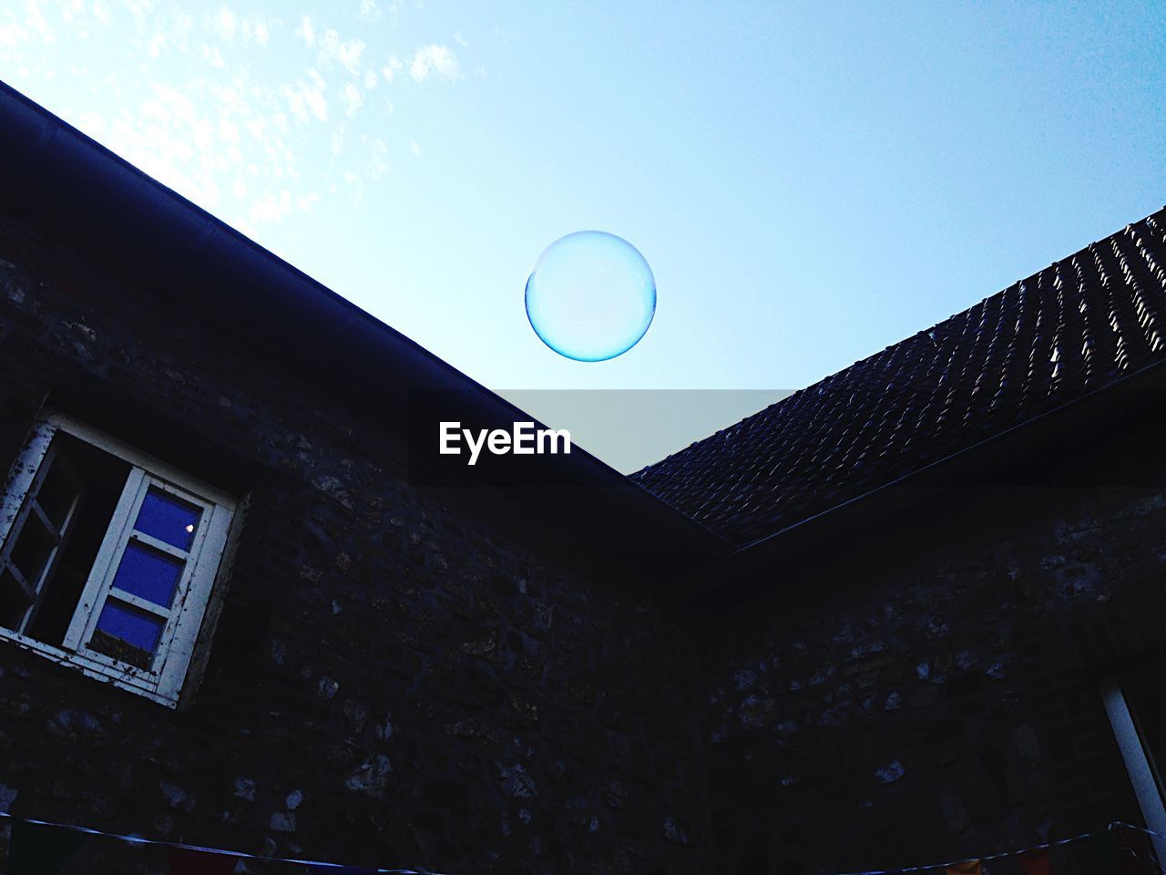 Low angle view of bubble and building against sky