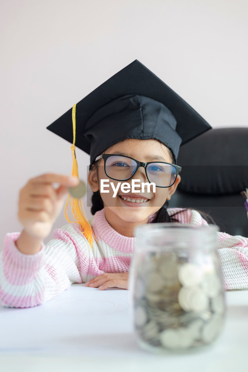 Portrait of boy holding eyeglasses on table