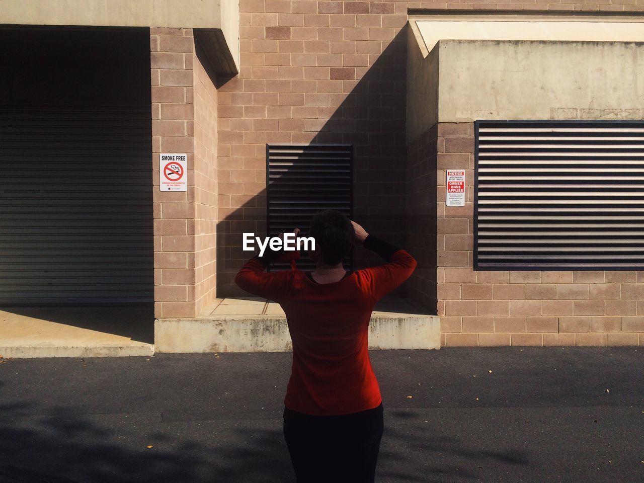 Rear view of woman standing against building on road