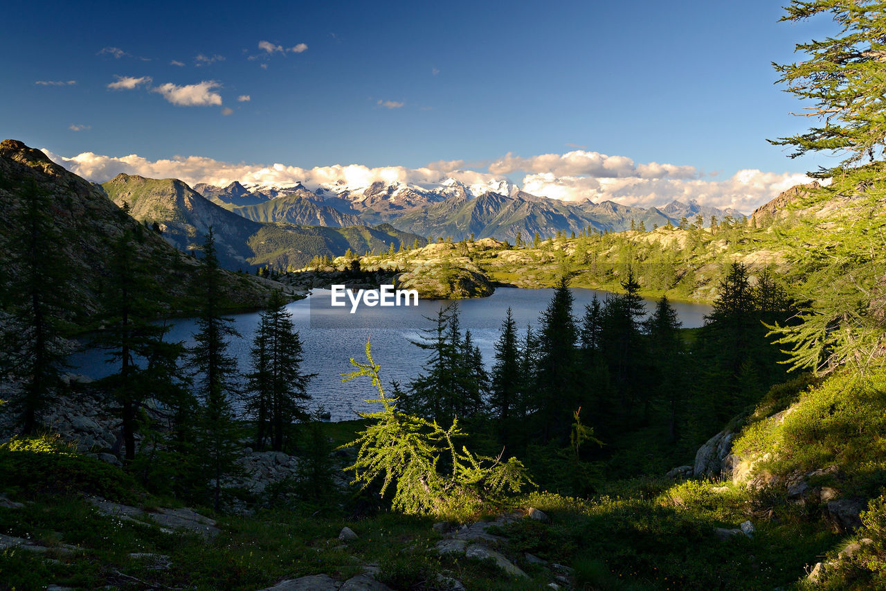 SCENIC VIEW OF MOUNTAINS BY LAKE AGAINST SKY