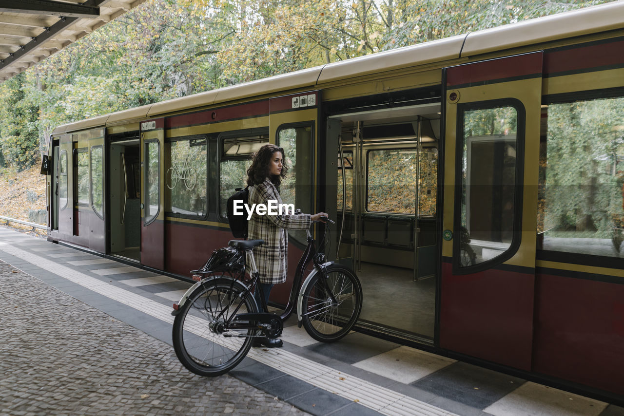 Woman with bicycle entering an underground train, berlin, germany