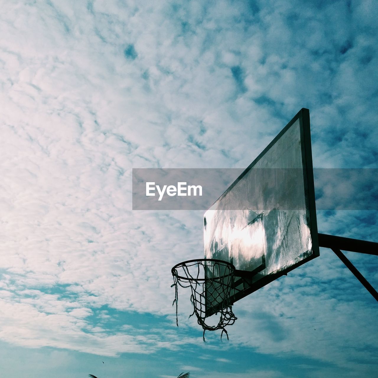 Low angle view of basketball hoop against cloudy sky