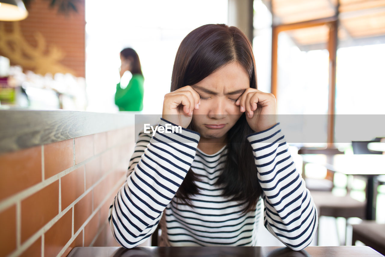 Young woman crying while sitting at restaurant