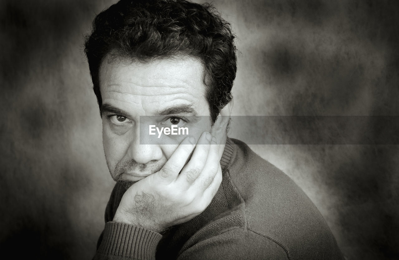 Close-up portrait of thought man against wall