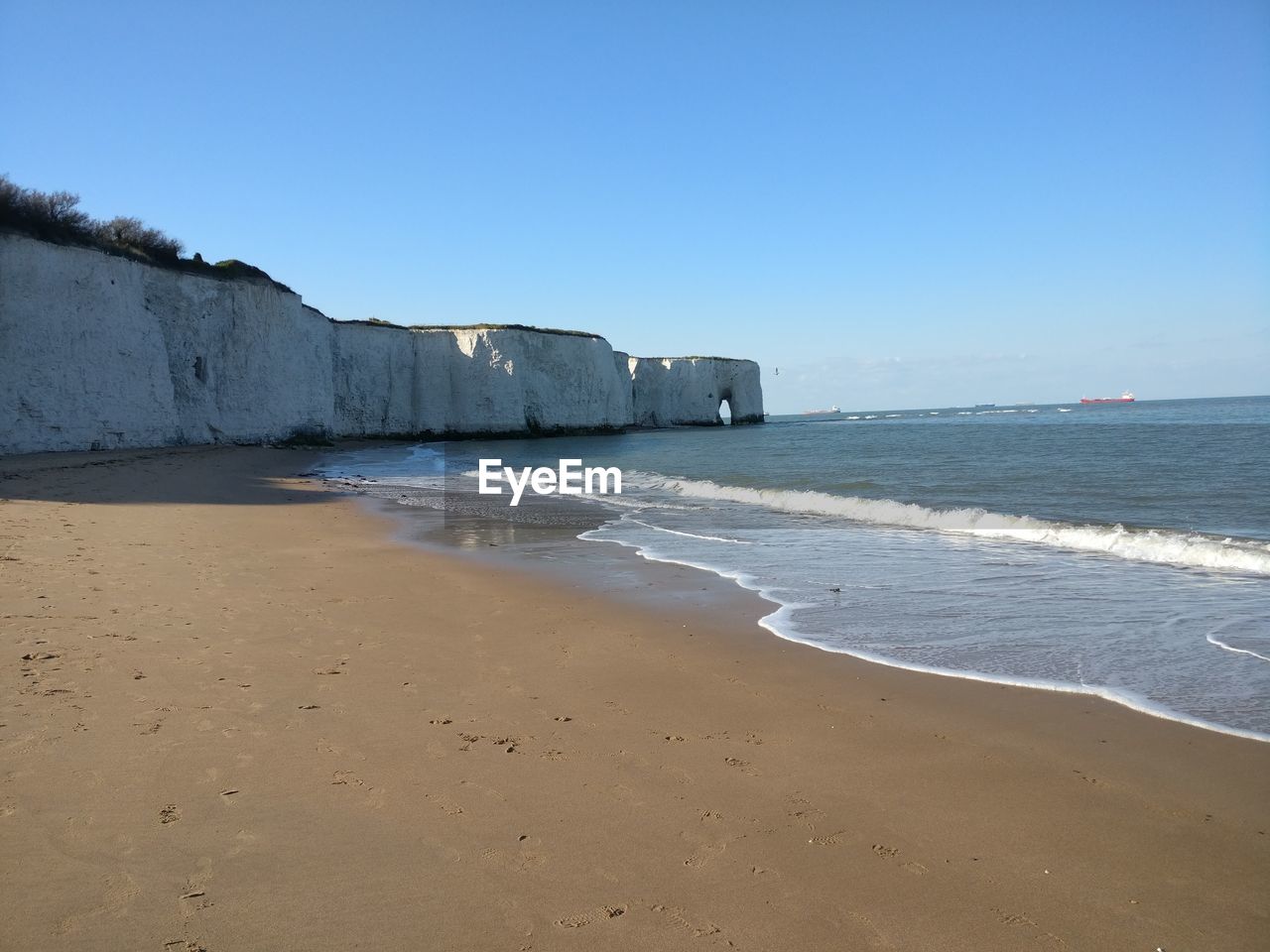 Scenic view of beach against clear blue sky