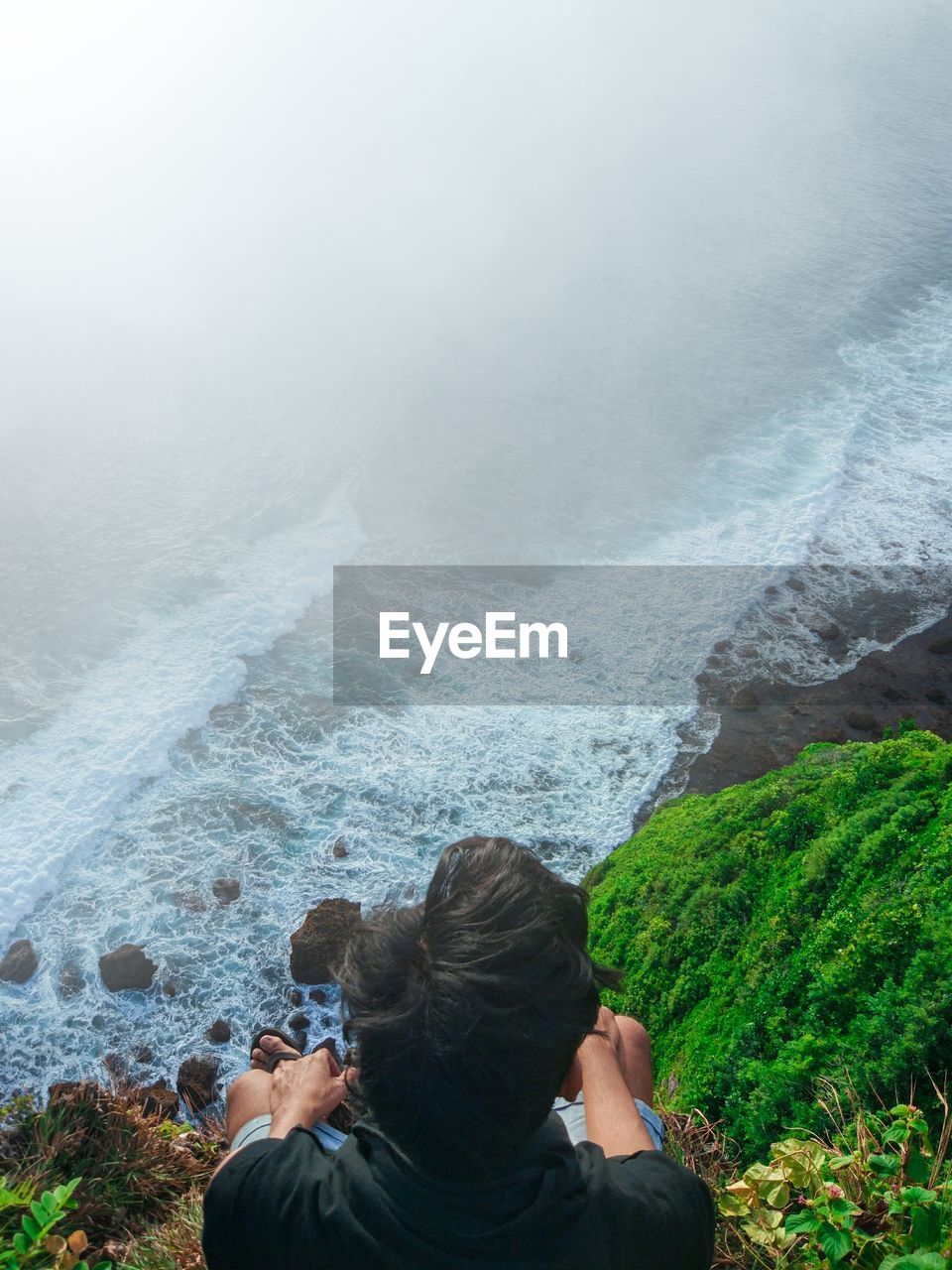 High angle view of man sitting on cliff