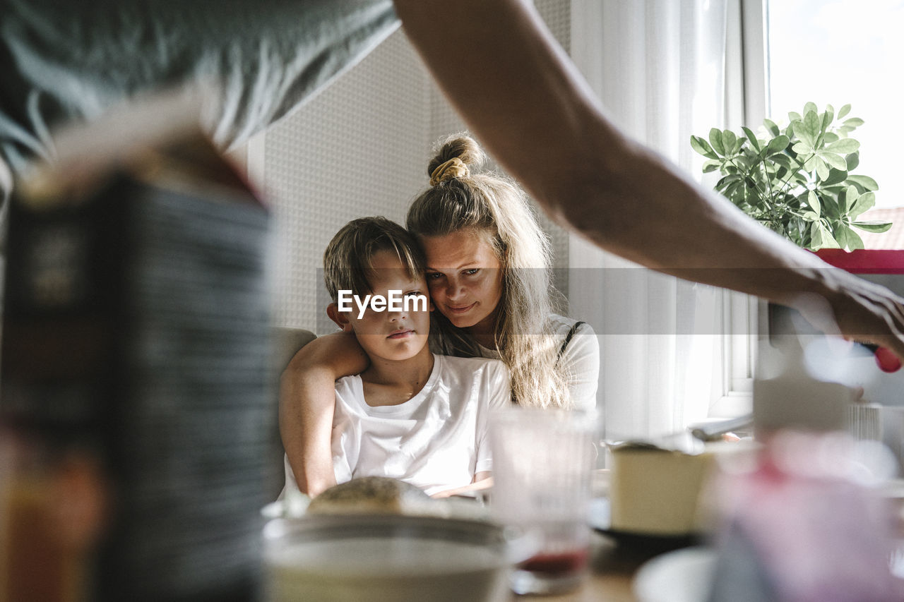 Mother embracing tired son at home