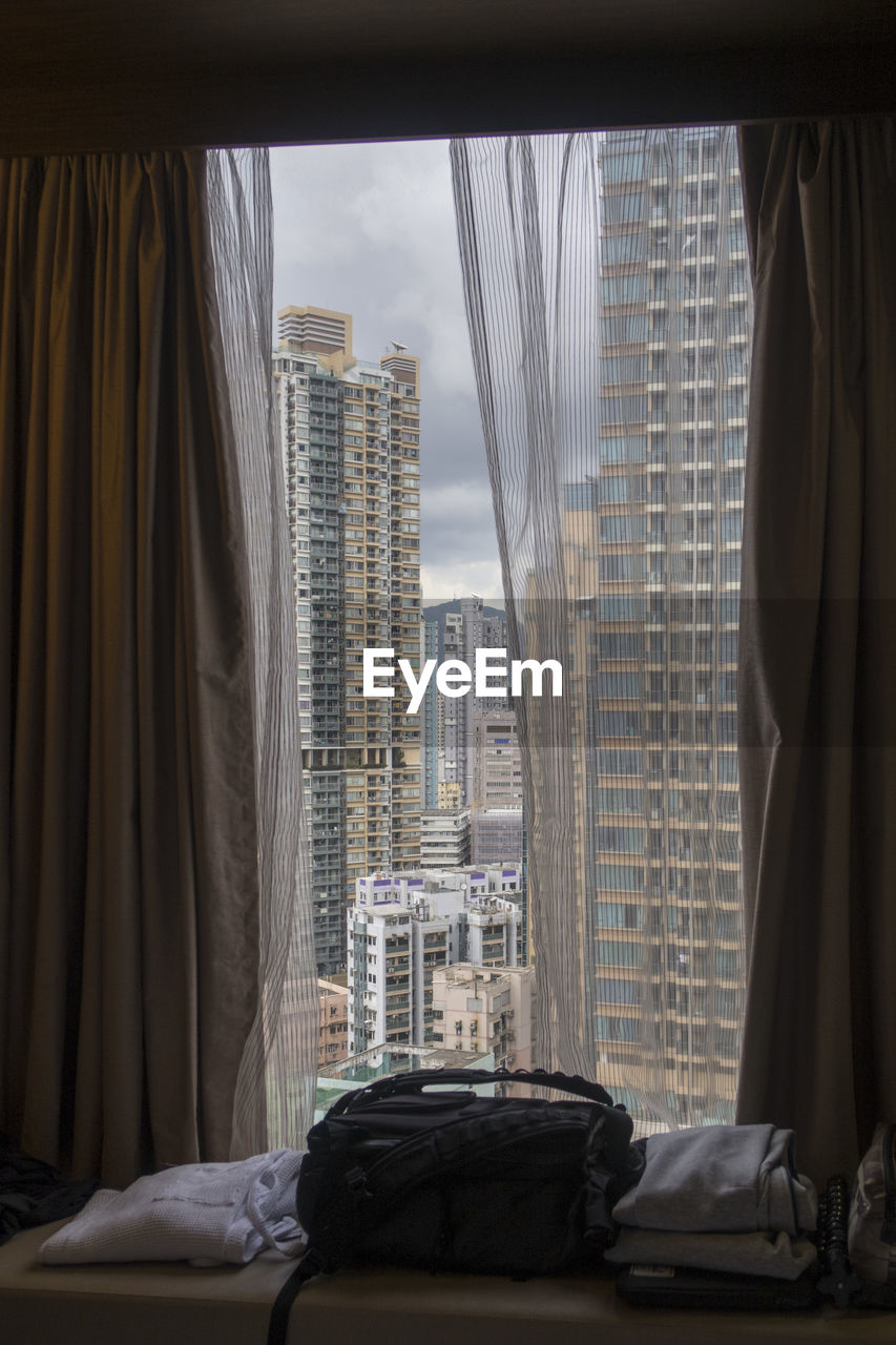 Buildings against sky seen through glass window, hong kong