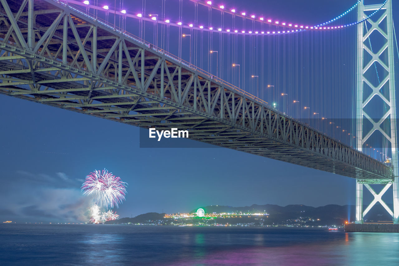 Low angle view of illuminated bridge over river at night