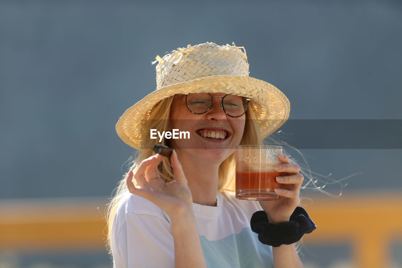 PORTRAIT OF A SMILING YOUNG WOMAN WITH HAT