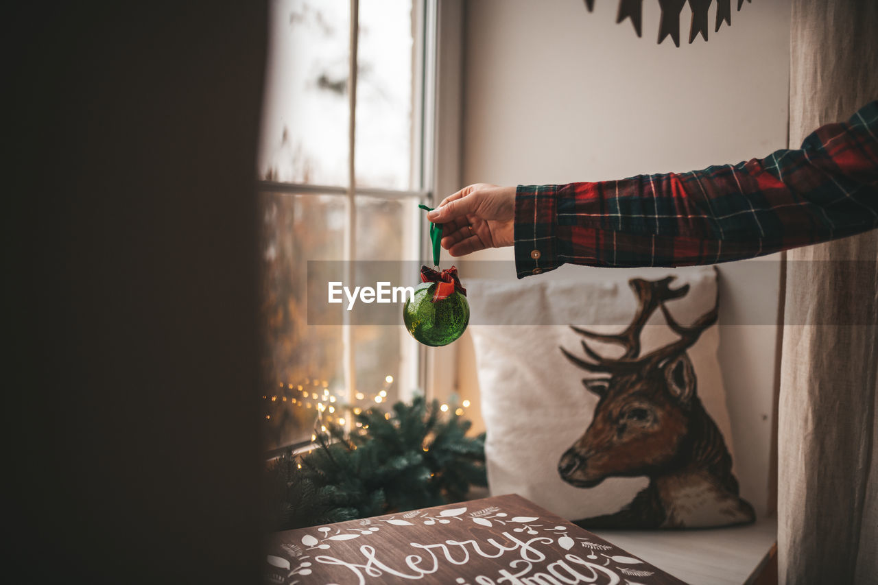 Cropped hand holding decoration at home