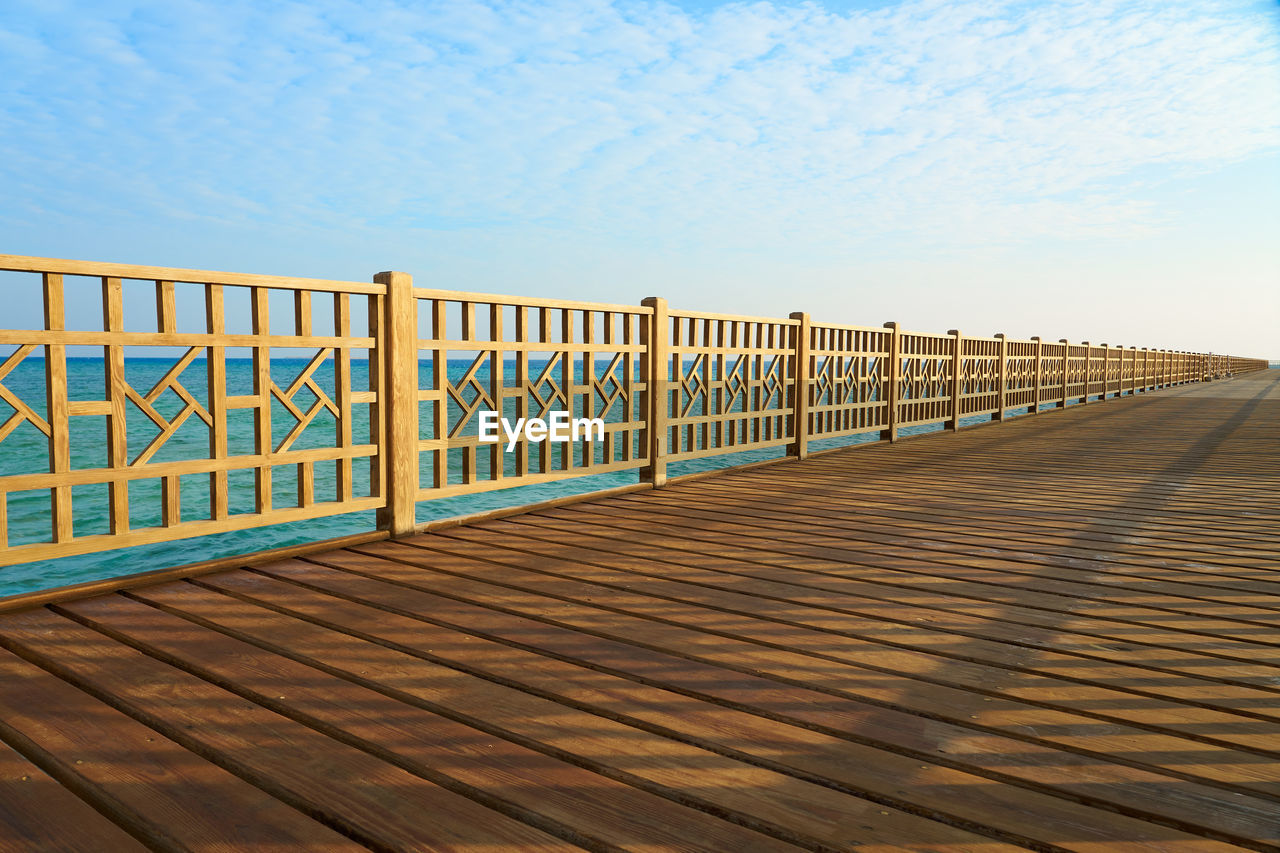 A wooden pier on the shores of the red sea with a horizon in the background.