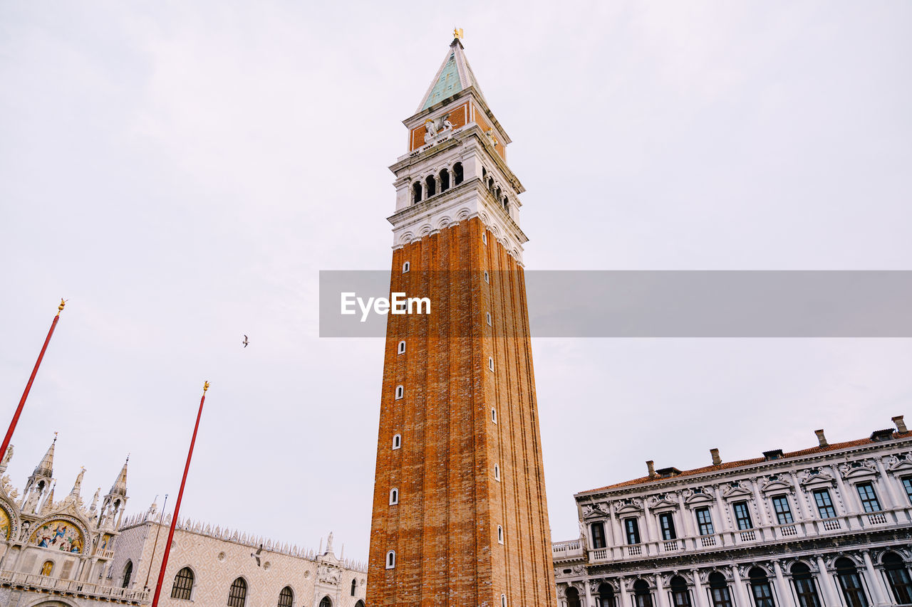 LOW ANGLE VIEW OF CLOCK TOWER AMIDST BUILDINGS IN CITY