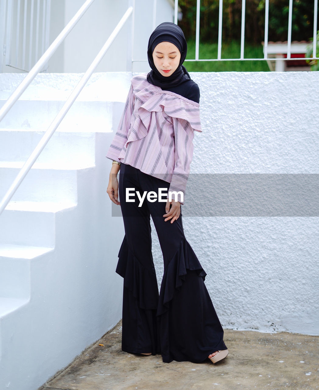 Young woman in headscarf looking away against wall