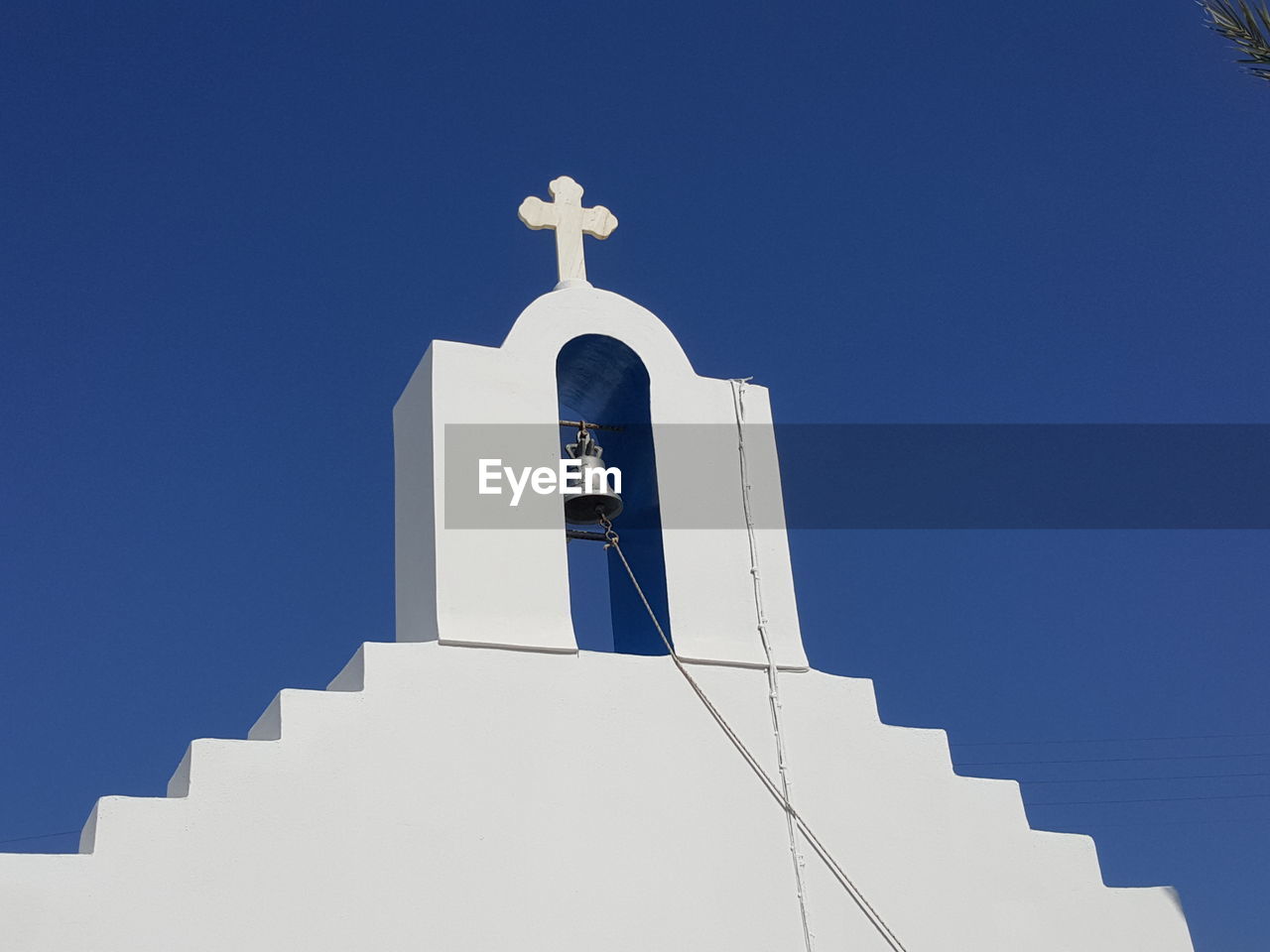 Low angle view of bell tower of church against clear blue sky at santorini