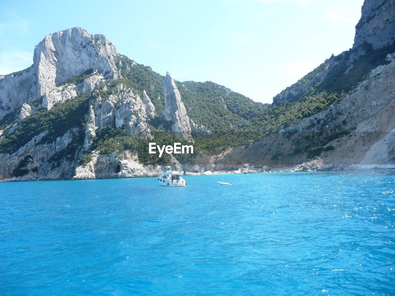 Boat in river against mountains during sunny day