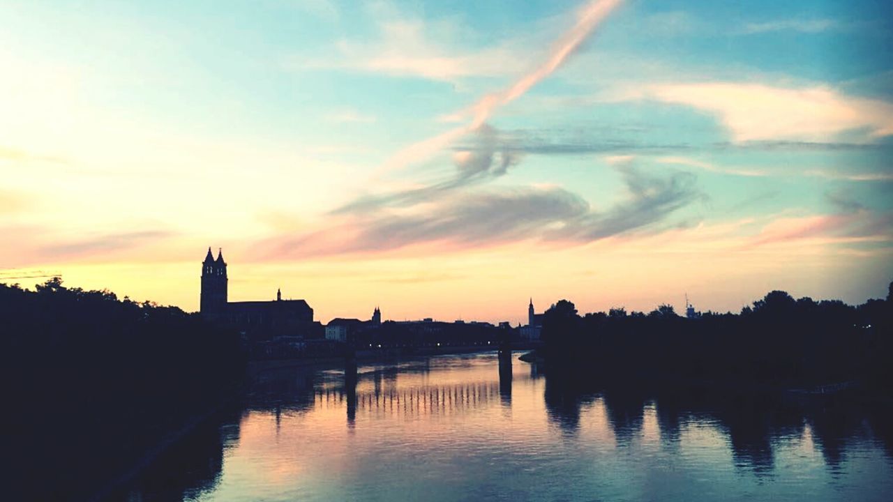 Scenic view of river against cloudy sky during sunset