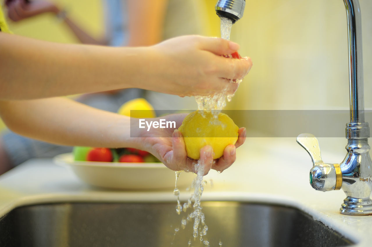 Cropped hand washing lemon in kitchen at home