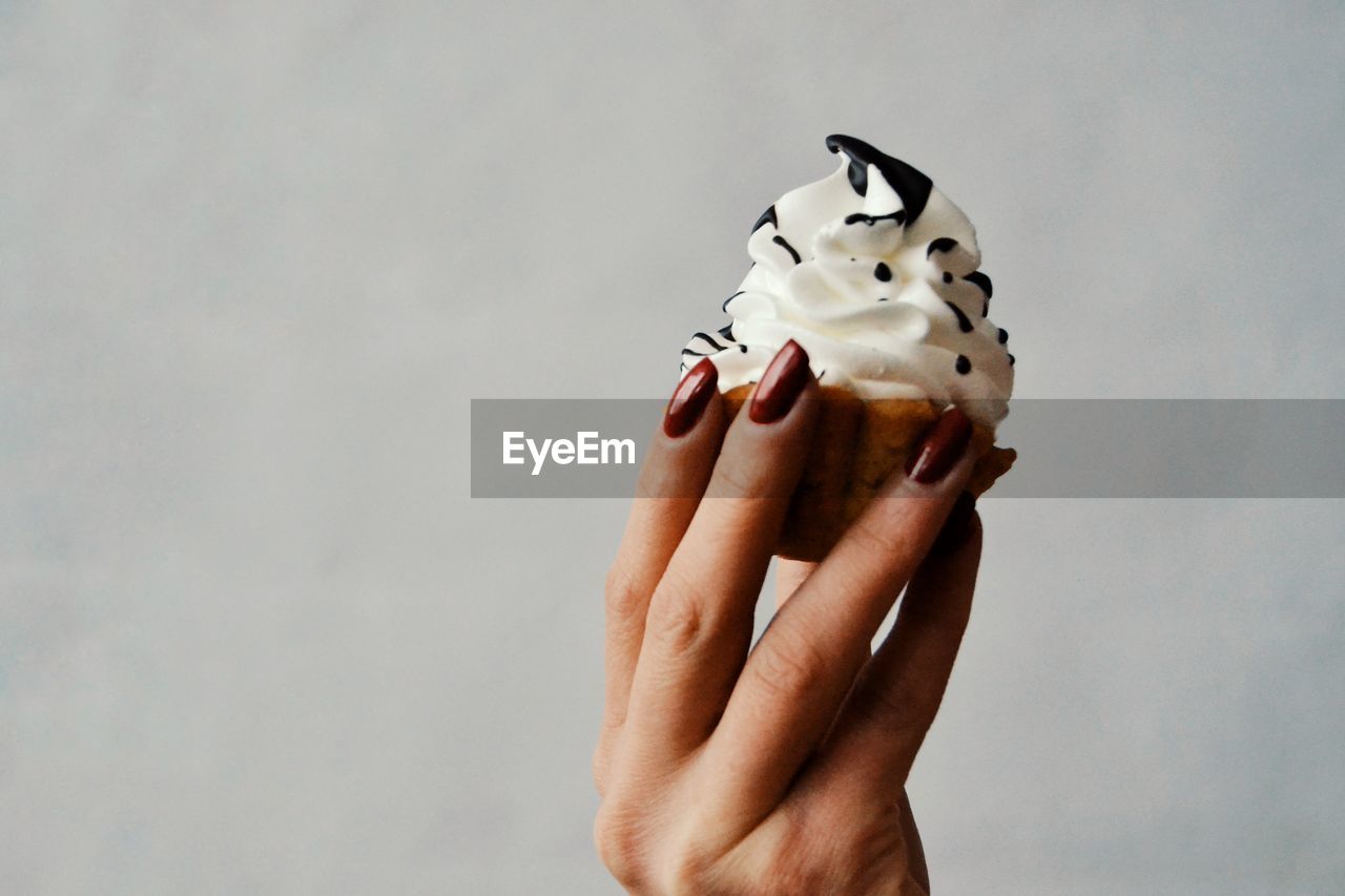 CLOSE-UP OF HAND HOLDING ICE CREAM CONE