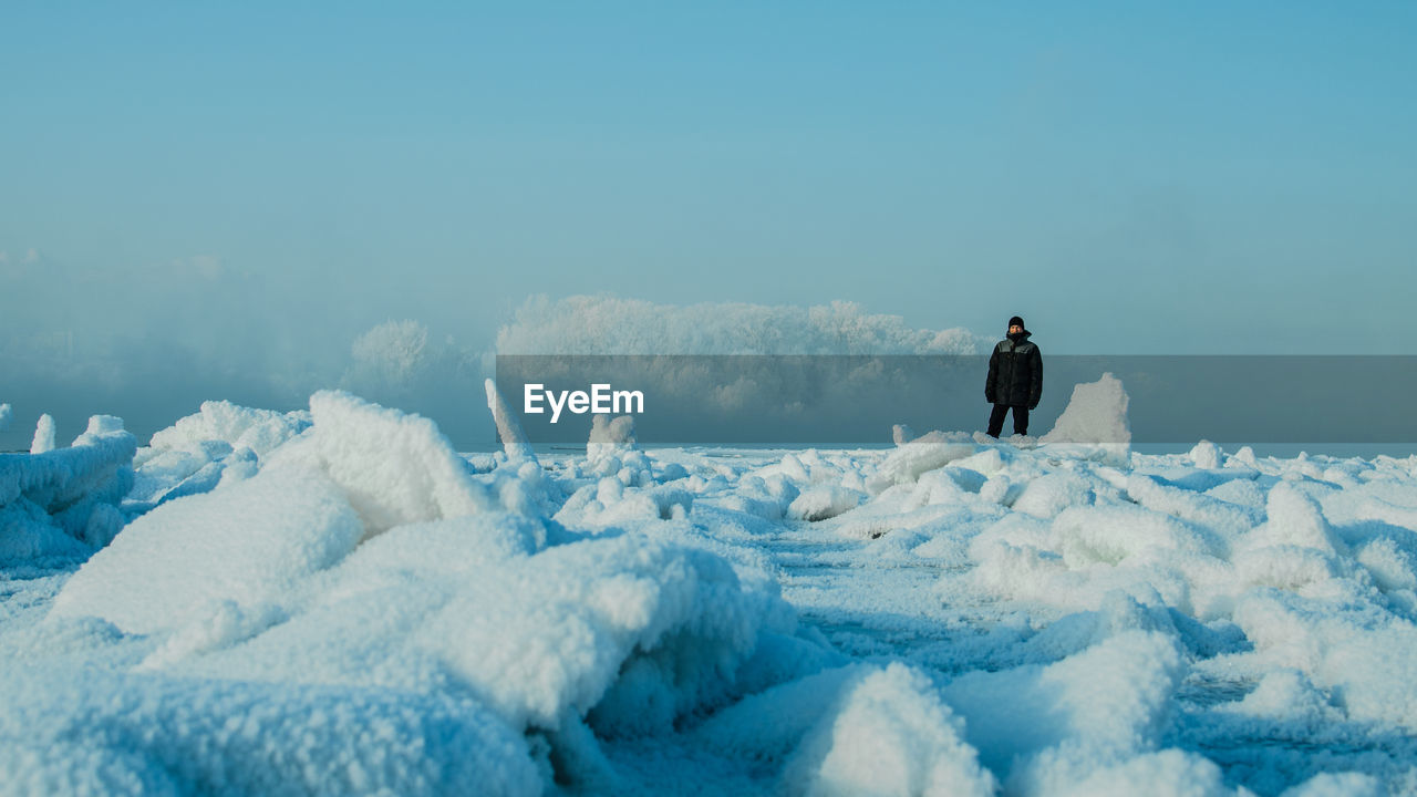 Man standing on snow covered land against sky