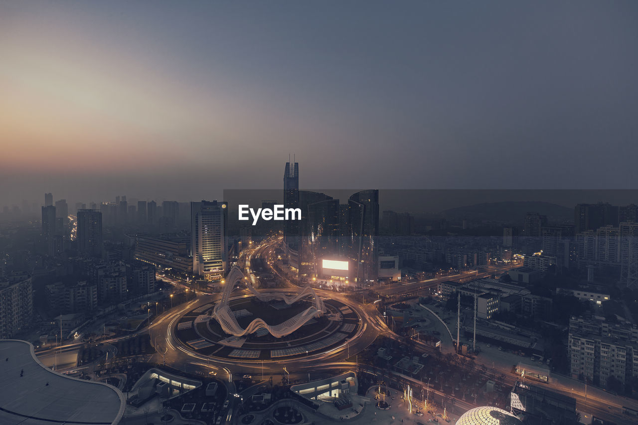 HIGH ANGLE VIEW OF ILLUMINATED CITY BUILDINGS AT NIGHT