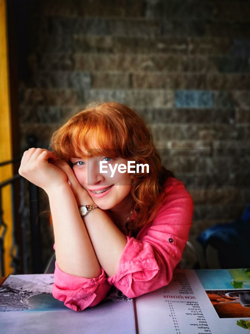 Portrait of smiling young woman leaning on table