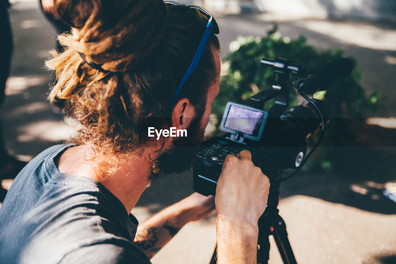 Young man with video camera by tree trunk