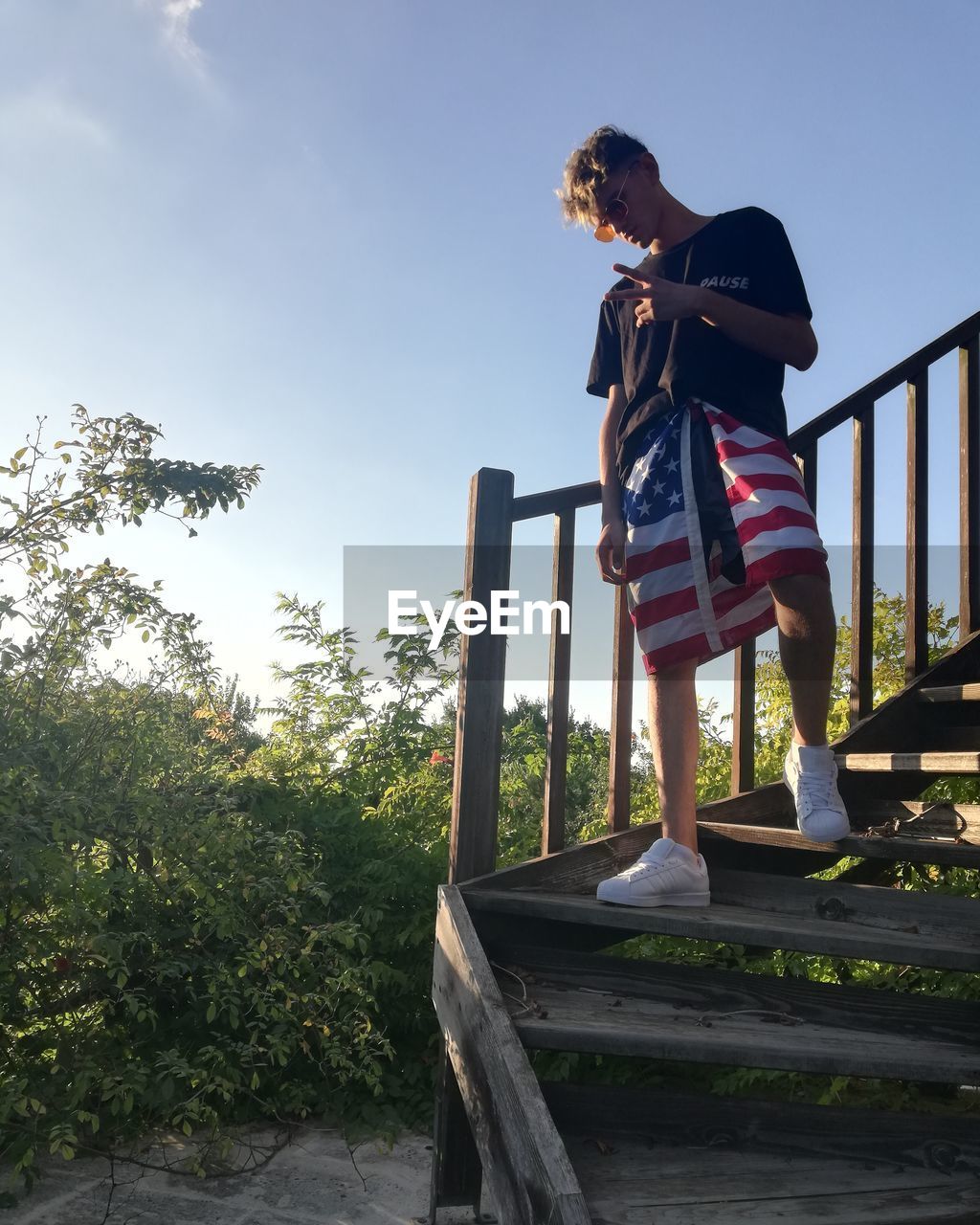 Boy standing by railing against sky