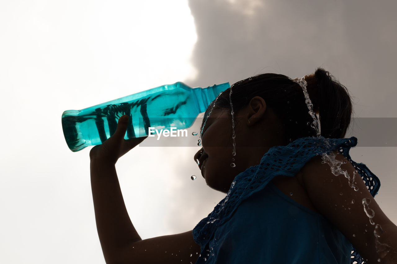 one person, blue, adult, women, young adult, sky, portrait, headshot, clothing, nature, side view, person, holding, waist up, female, lifestyles, emotion, cloud, outdoors