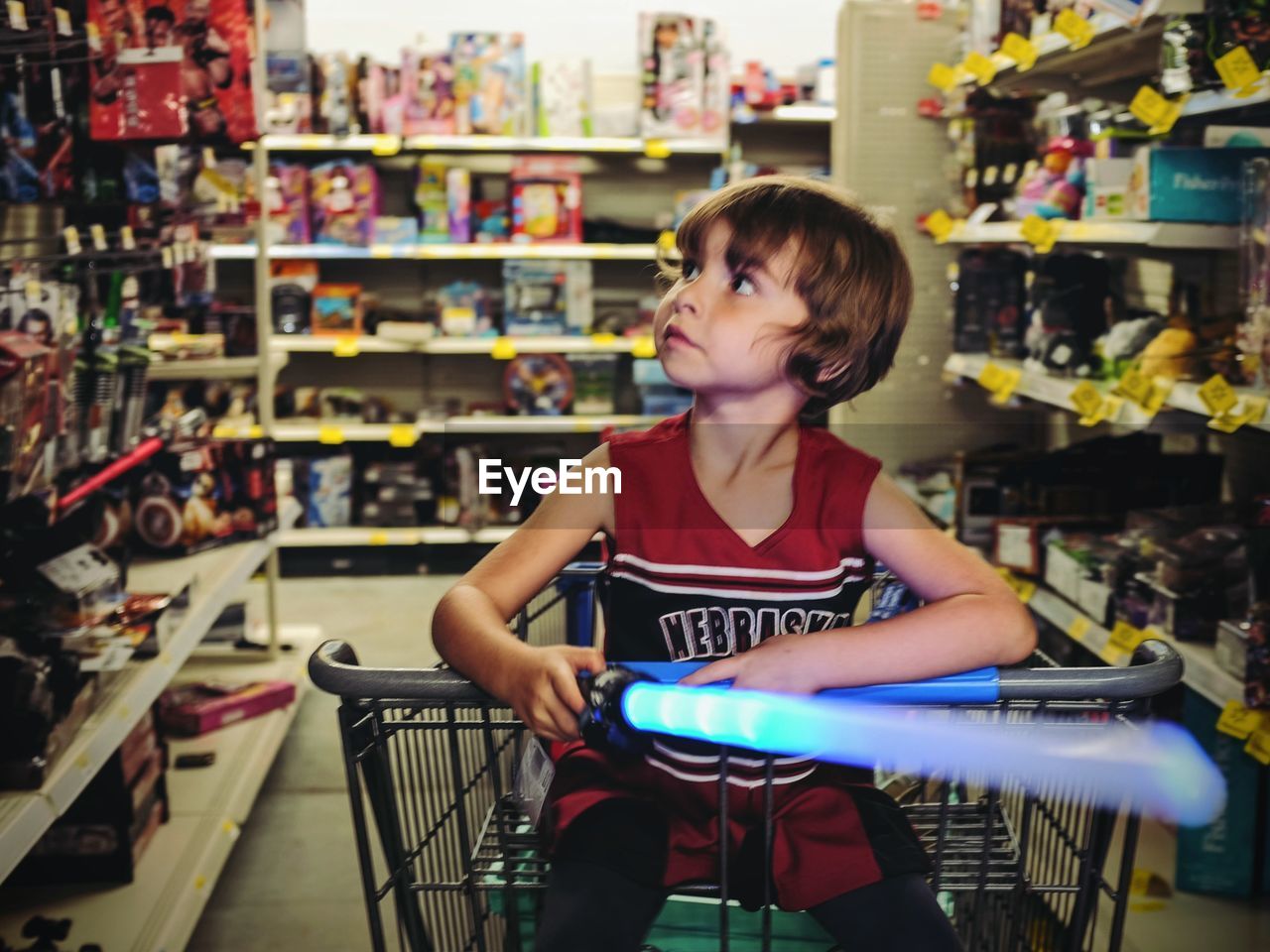 Boy sitting in shopping cart at toy shop