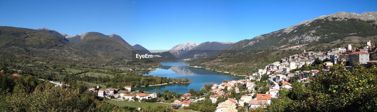 Panoramic view of lake and buildings against clear blue sky