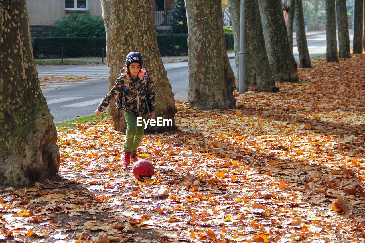 Full length of boy playing with ball on field during autumn