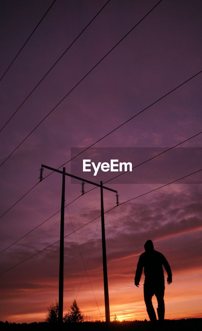 Low angle view of silhouette man standing against sky during sunset