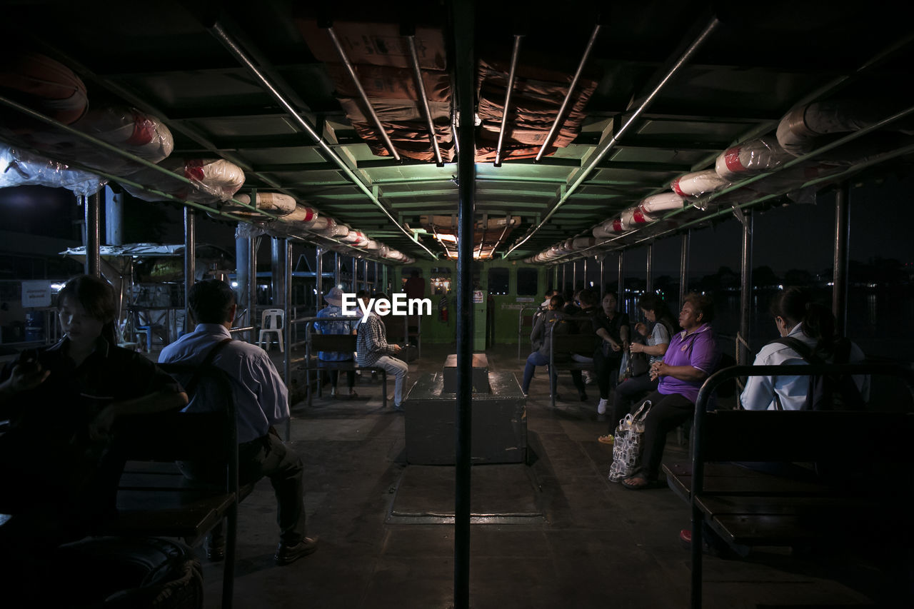 PEOPLE SITTING IN ILLUMINATED UNDERGROUND WALKWAY