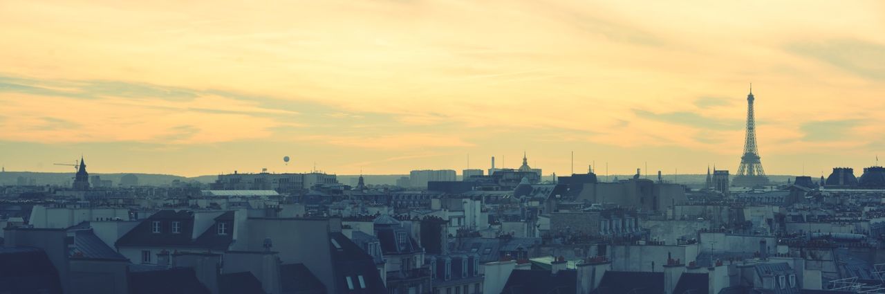 Eiffel tower with cityscape against orange sky during sunset