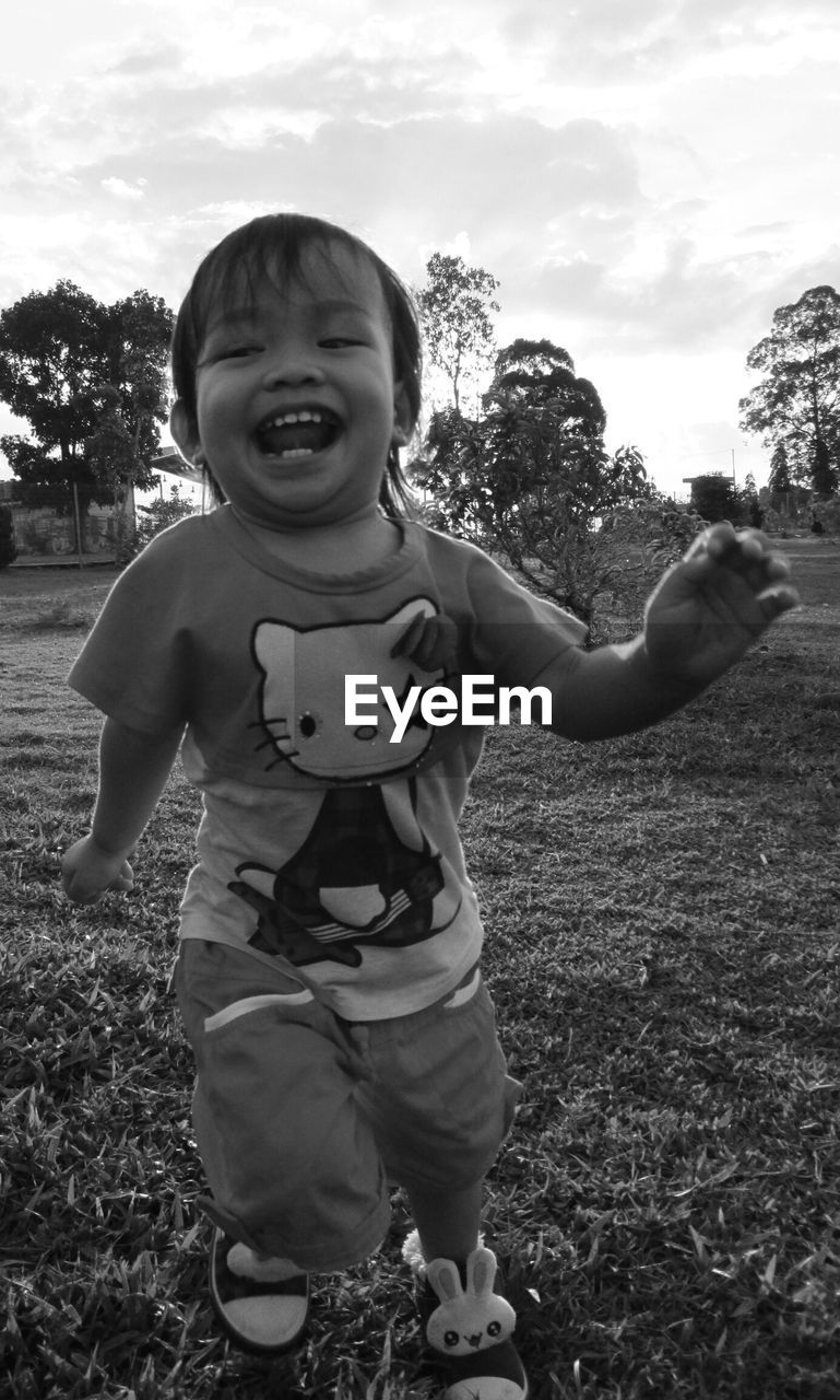 PORTRAIT OF SMILING BOY STANDING ON GRASSY FIELD