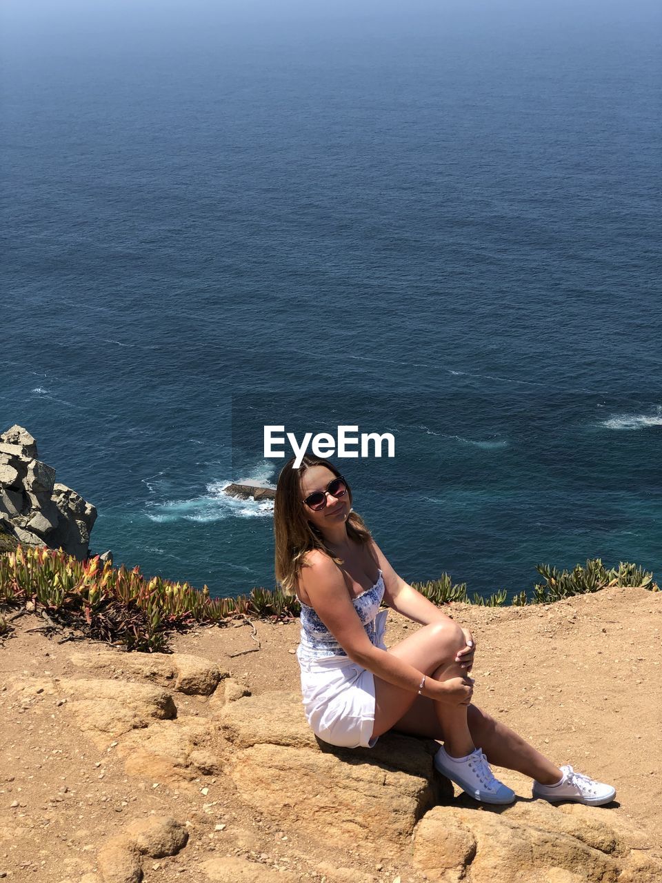 WOMAN SITTING AT BEACH