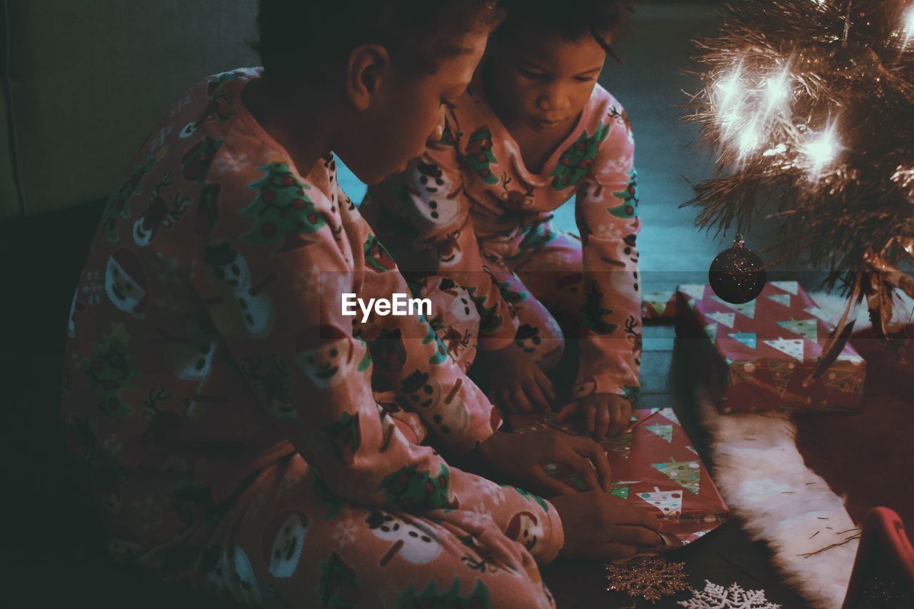 High angle view of girls opening gift while sitting at home