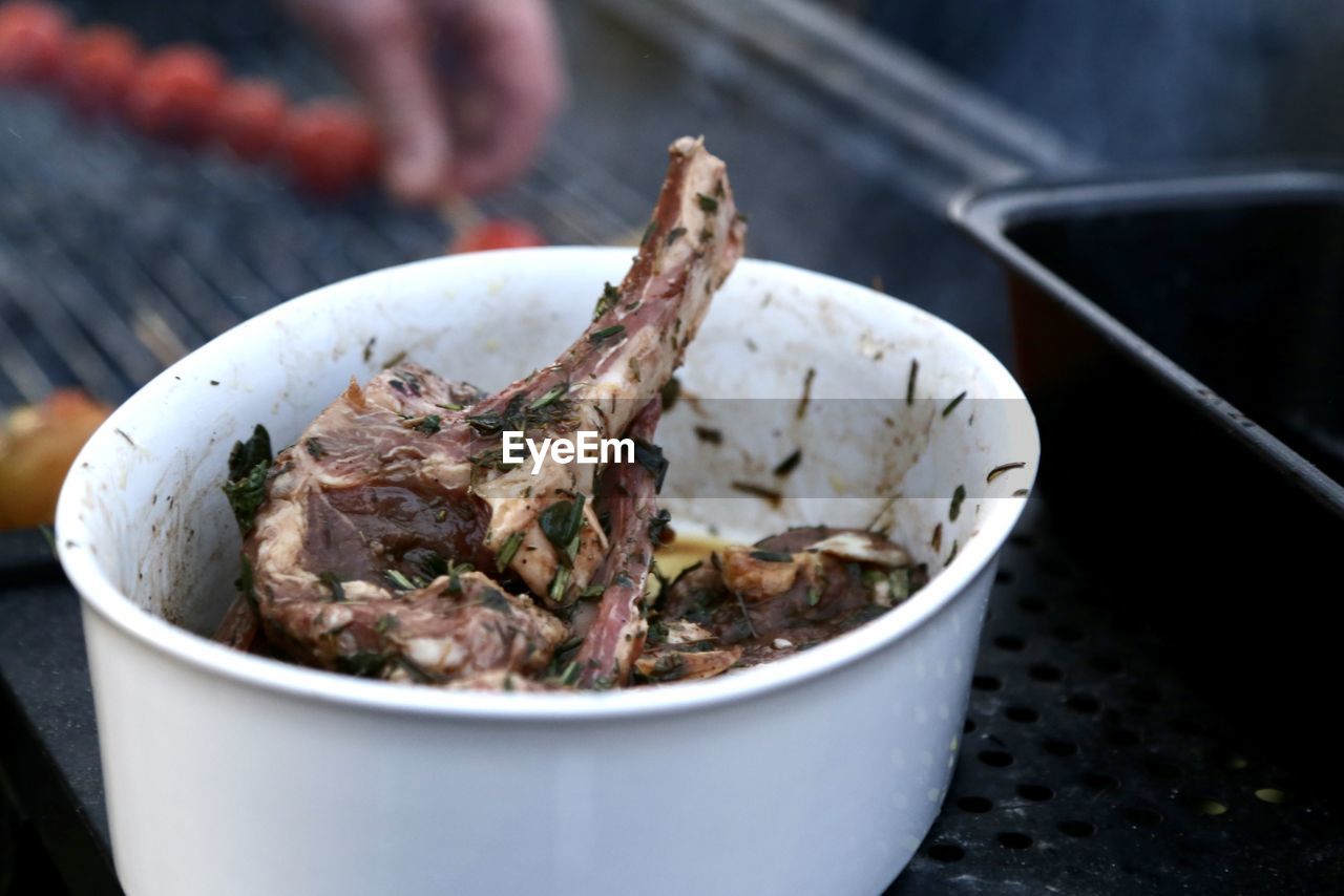 High angle view of meat in bowl standing outdoors on the grill waiting to be grilled 